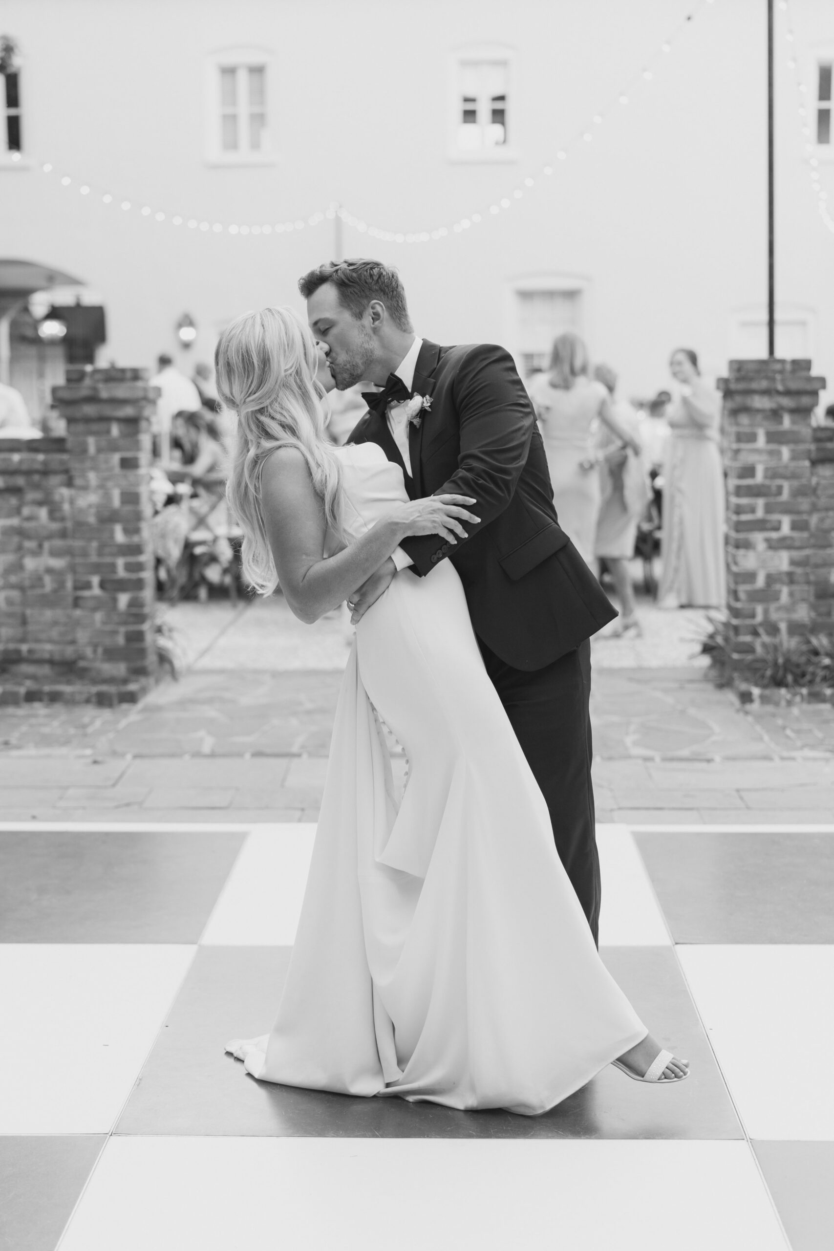 black and white wedding photo. Groom dips bride back for a sweet kiss on the dance floor.