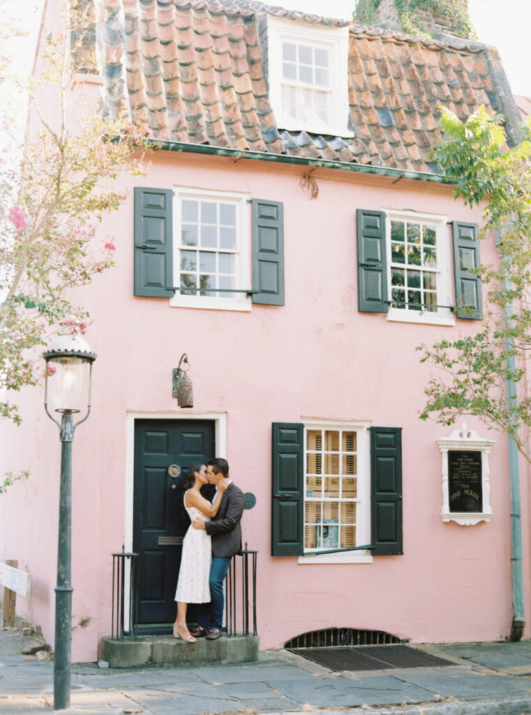 Charleston engagement session. Couple kissing on the step of old pink house in downtown Charleston. 
