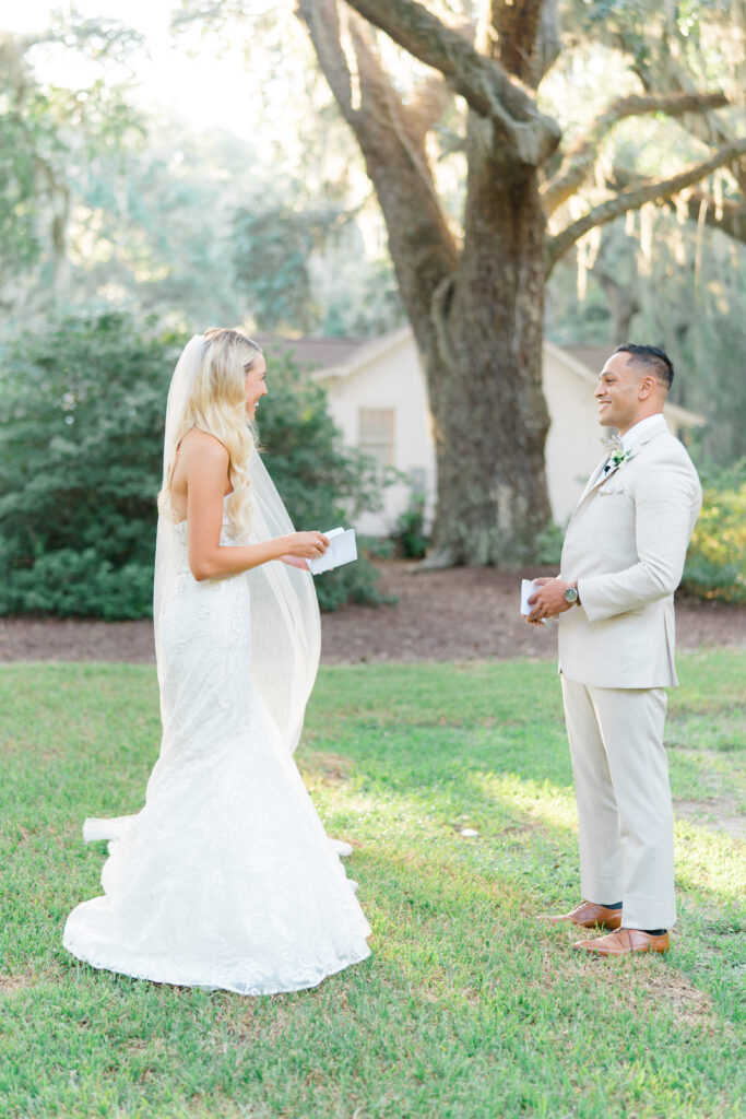 Bride and groom laugh with each. Big tree and spanish moss in background. 