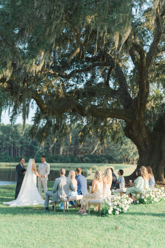 Intimate wedding ceremony under a tree with spanish moss blowing in the wind. Small guest count destination wedding in Charleston, SC.