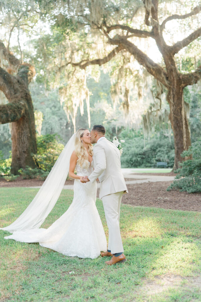 Bride and groom kiss with live oak trees and spanish moss. 