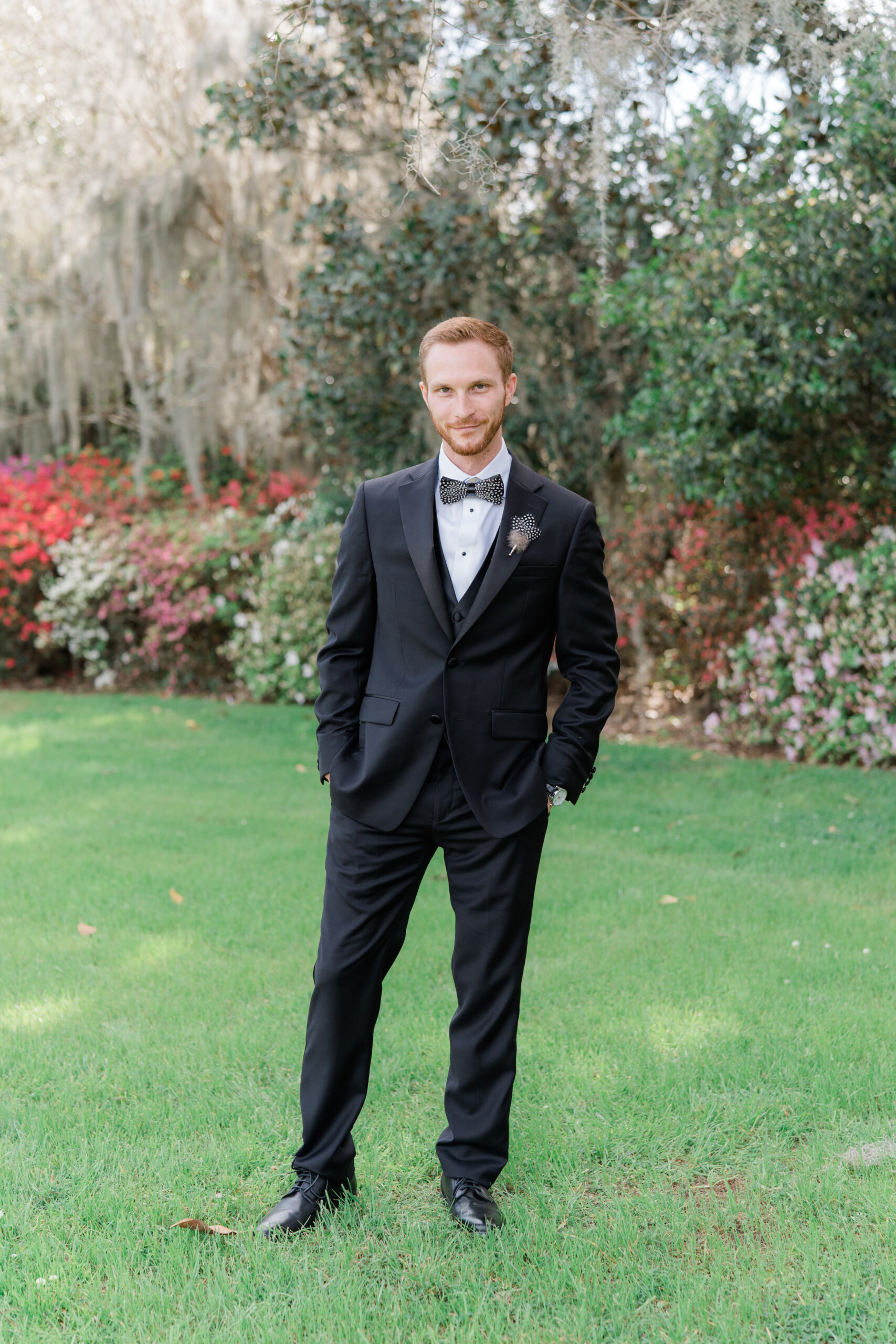Groom with red hair and a Brackish bowtie in the gardens at Middleton Place during spring azalea blooms. 