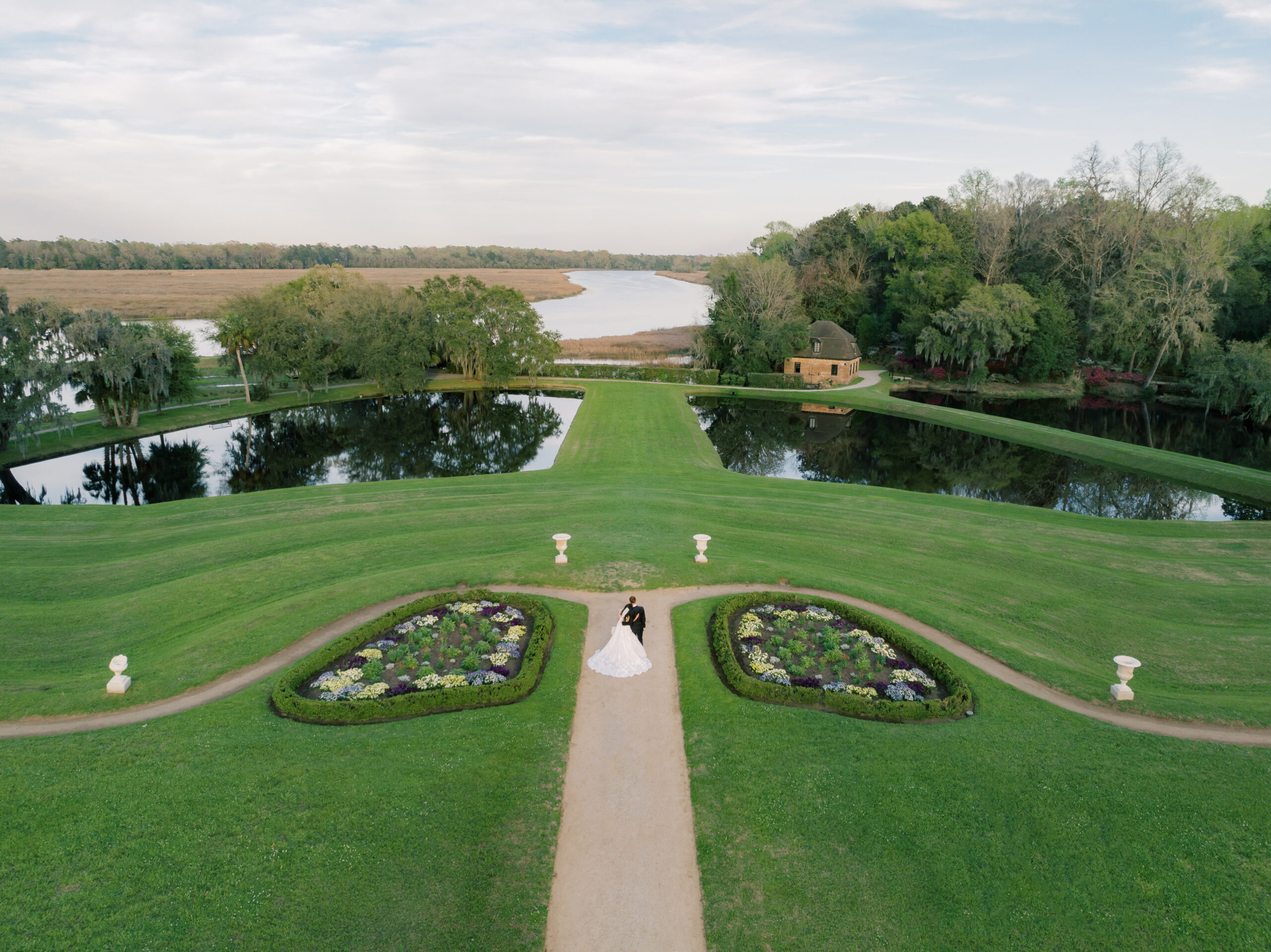 Bride and groom look out over the river at Middleton Place during sunset. 
