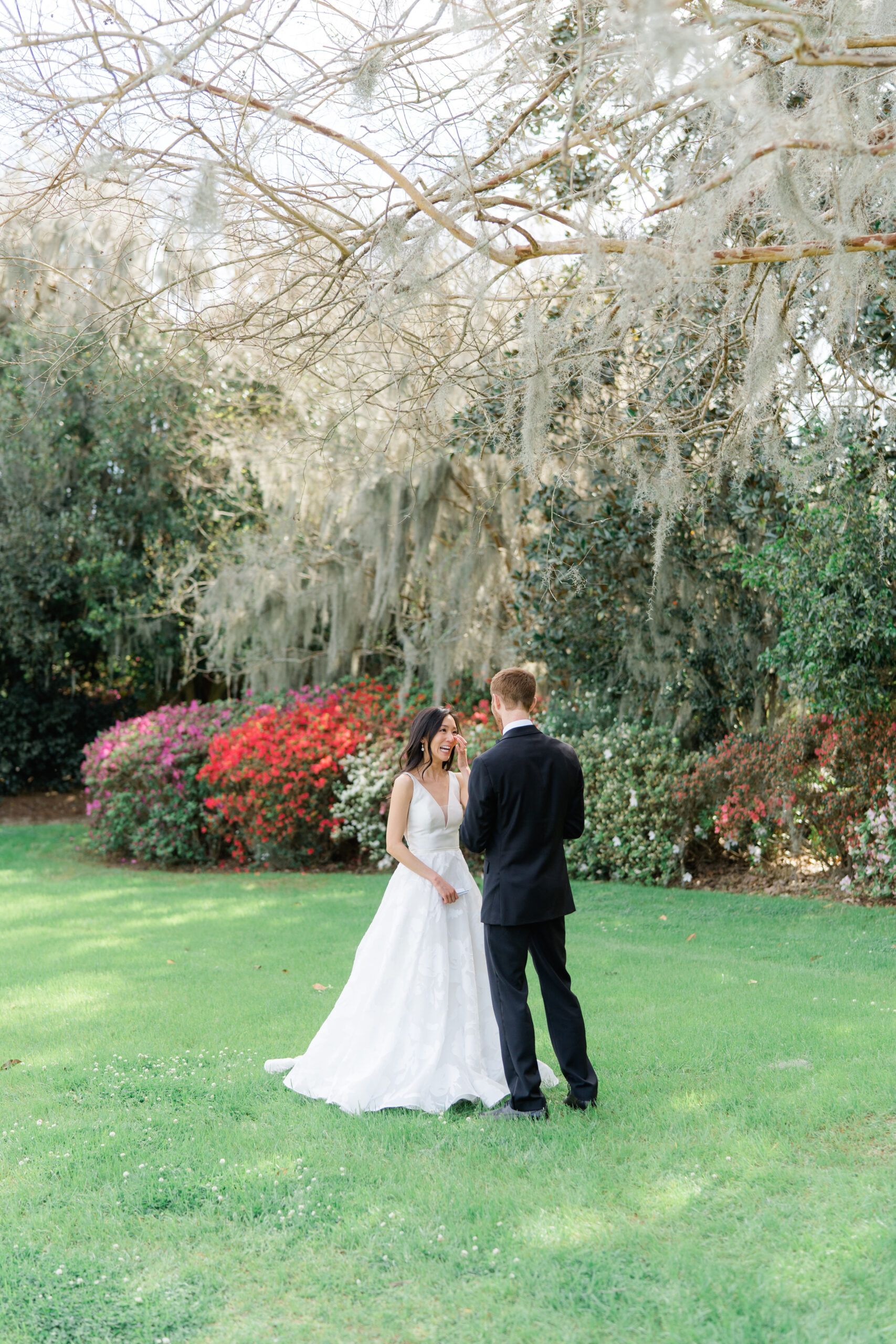 Bride wipes away a tear during private vow reading with the groom. Perfect wedding day with azalea flower blooms and spanish moss. 