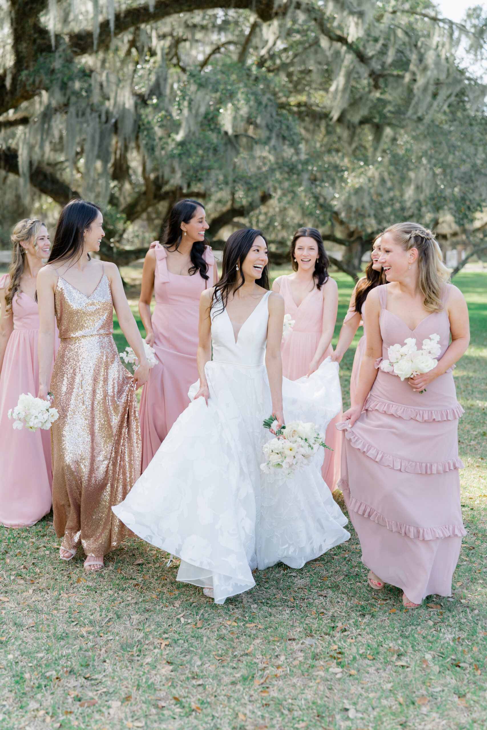 Bride and bridesmaids walking together. Maid of honor in bold pop of color dress. Shimmering gold dress. Middleton Place wedding photographer. 