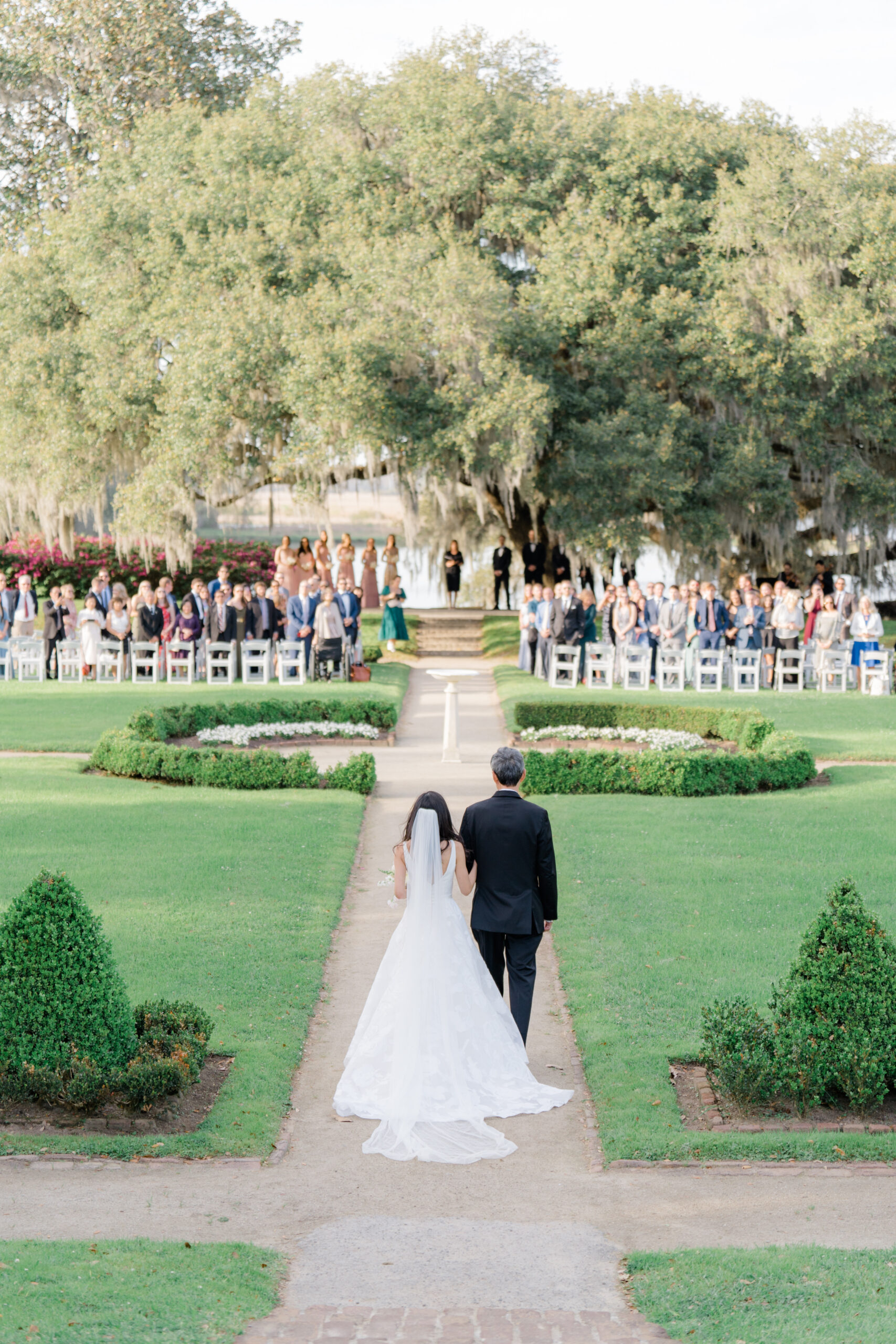 Bride escorted by her day to wedding ceremony in the octagonal garden at Middleton Place spring wedding. photographer wedding Charleston. 