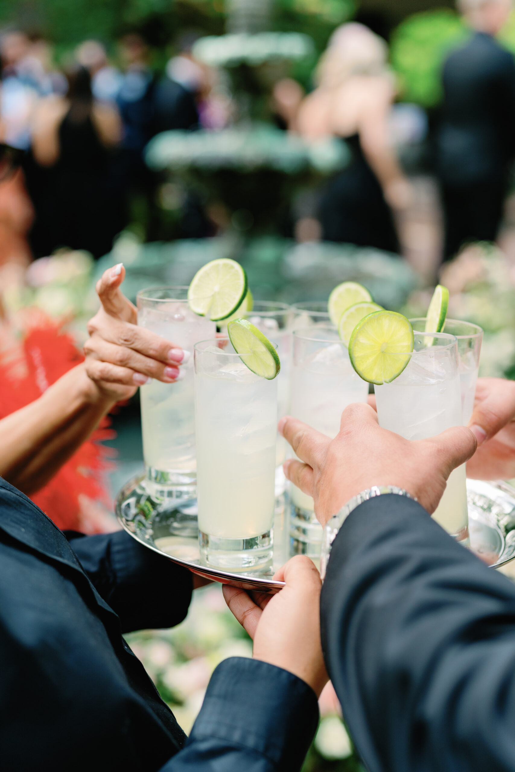 Wedding guests grab cocktails with lime garnish off of tray at spring cocktail hour. Charleston destination wedding.
