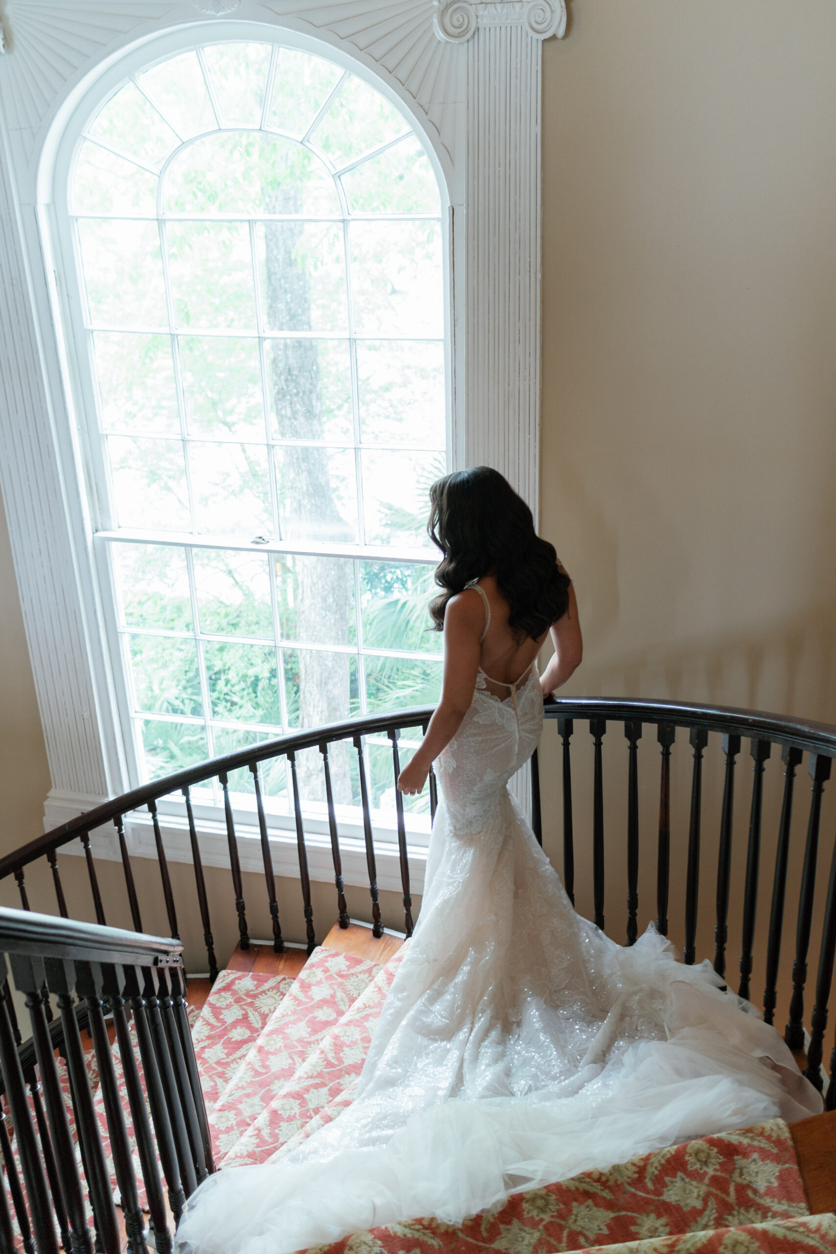 Bride walking down curved staircase in historic charleston home.