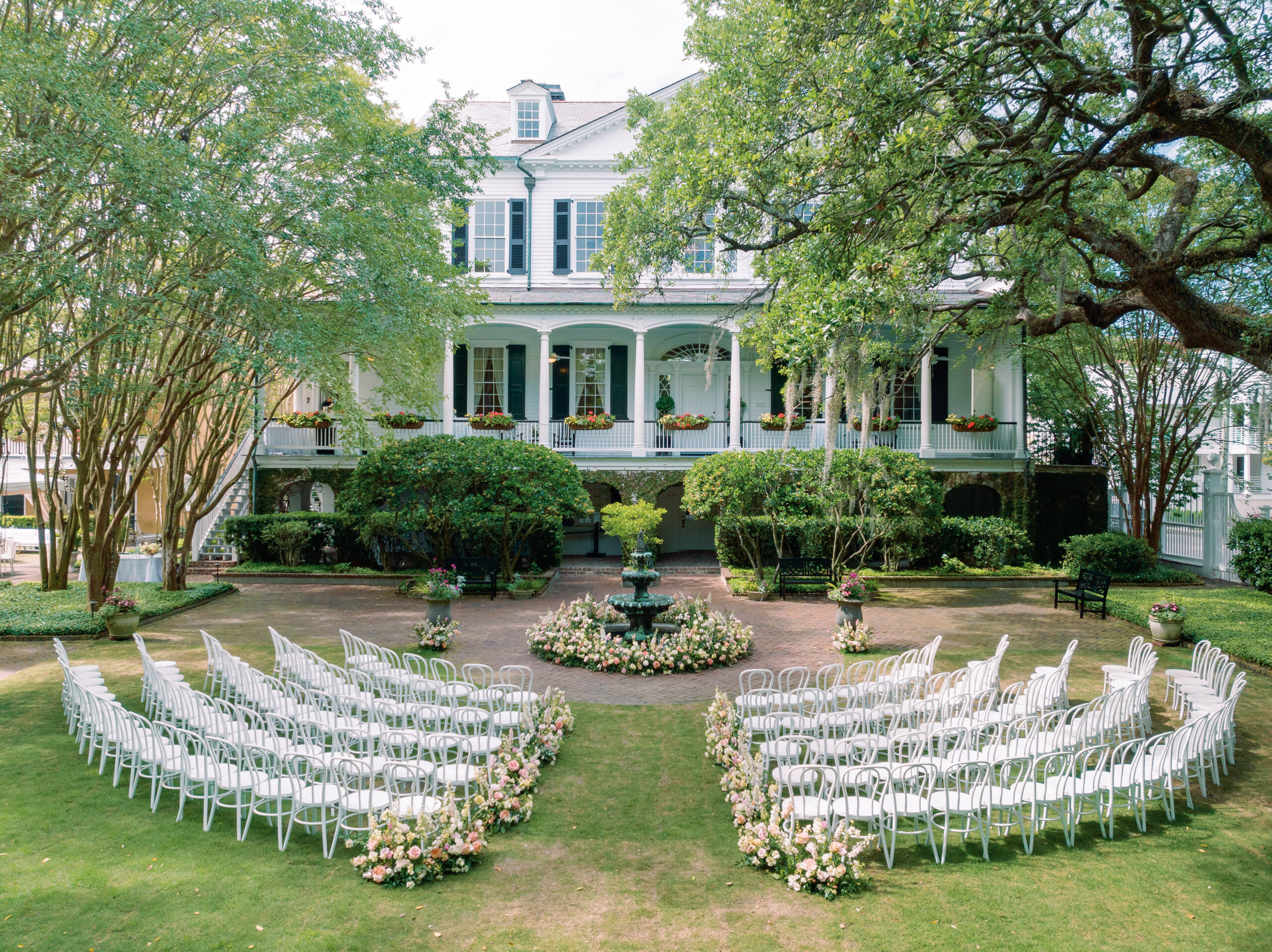 Thomas Bennett House spring wedding ceremony with white chairs and pink and white flowers. 