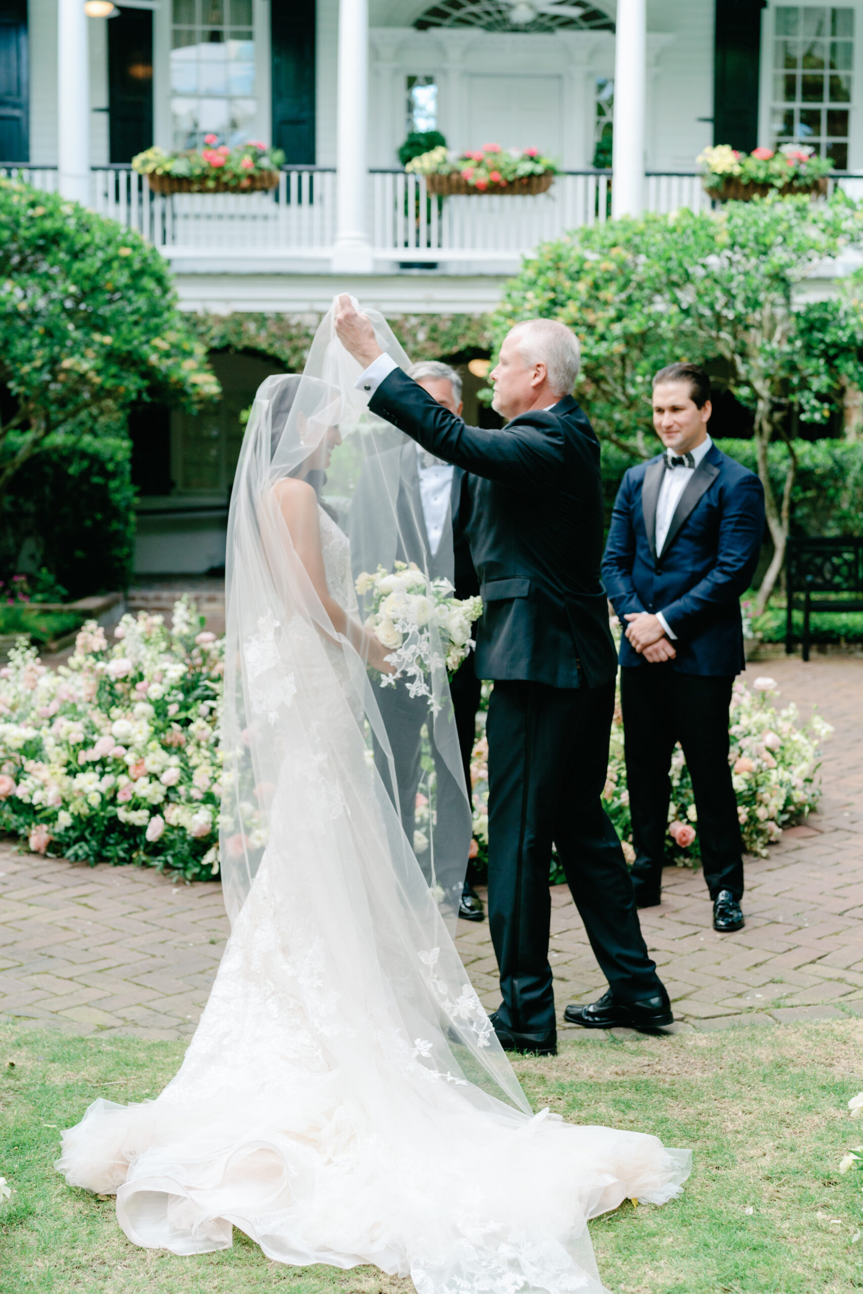 Father of the bride lifts veil at wedding ceremony.