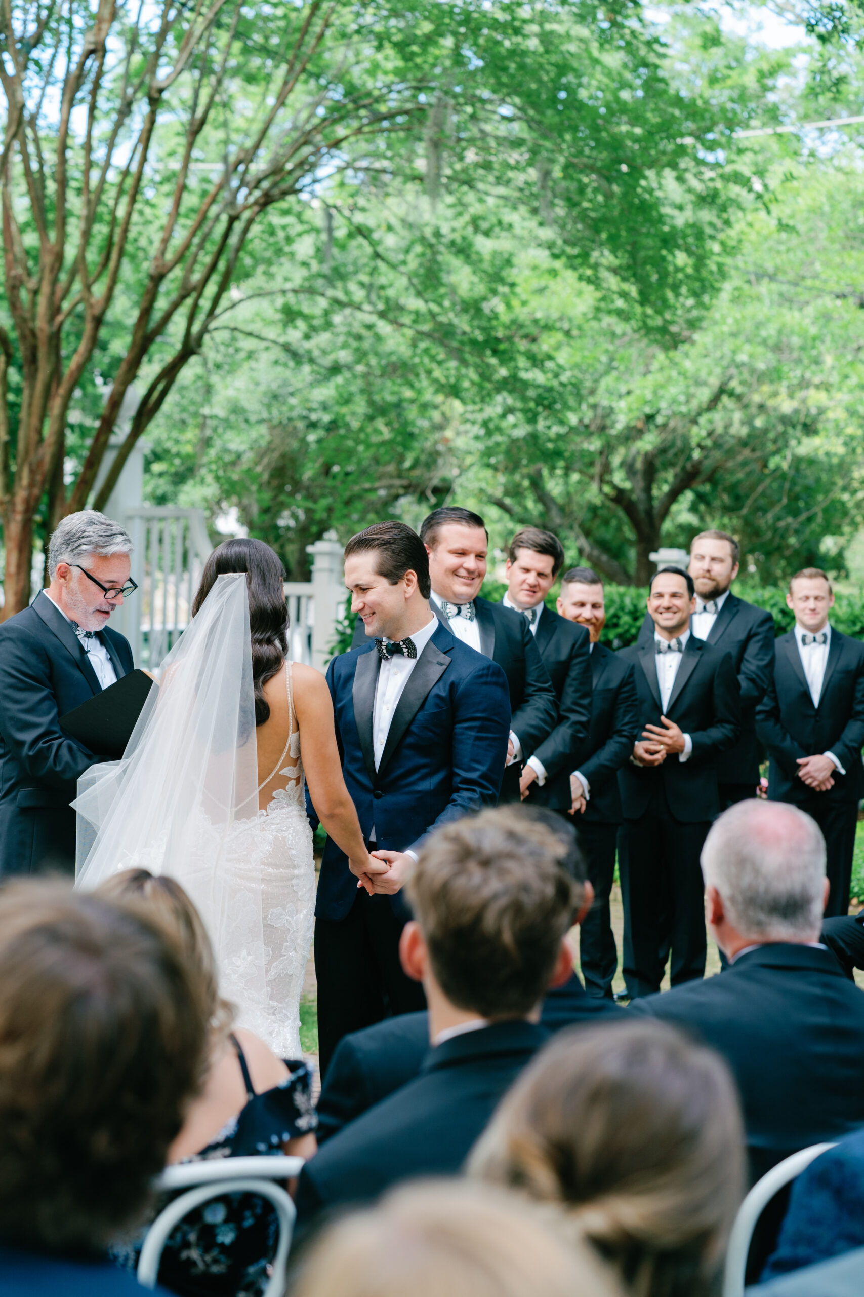 Groom and groomsmen laugh and smile during wedding ceremony.
