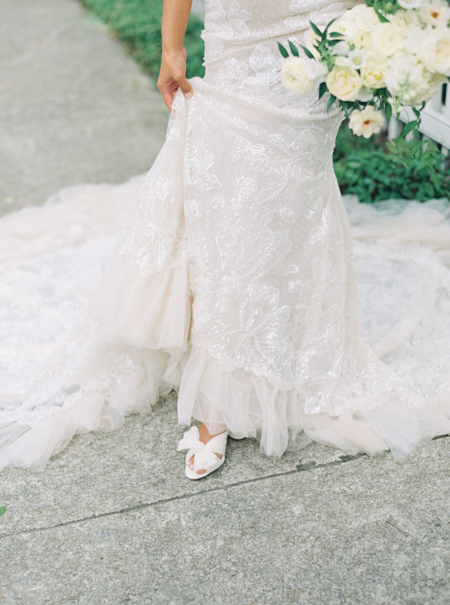 film photo of bride holding dress with heels popping out.