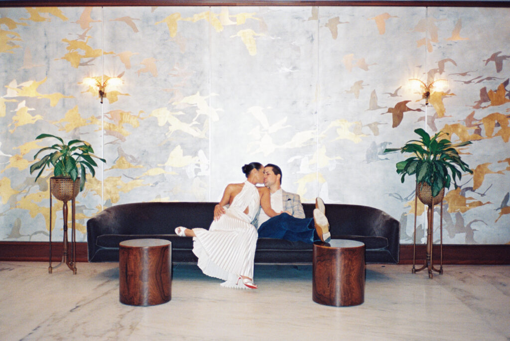 Flash film photo of couple kissing on the couch.