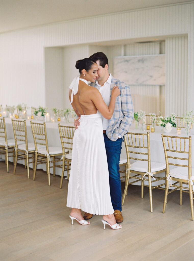 Bride in halter top white dress for wedding welcome party. Groom in jeans, white collar shirt and grey and blue patterned jacket. charleston sc photographer.