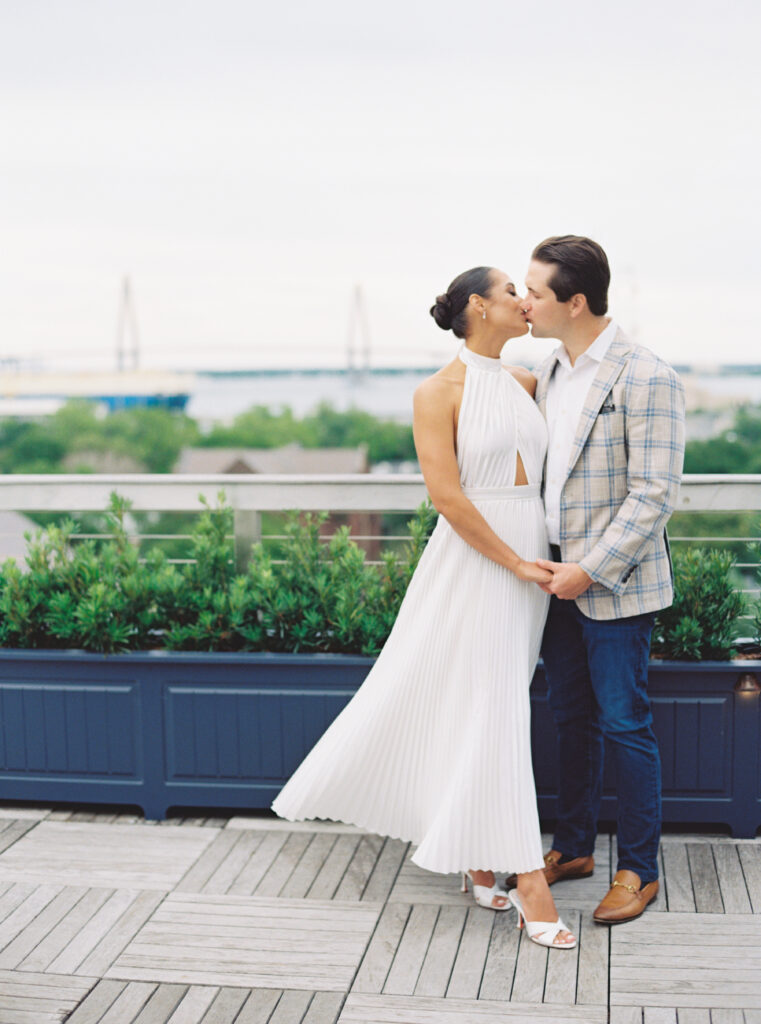 Film photo of couple kissing with Ravenel bridge in the background.