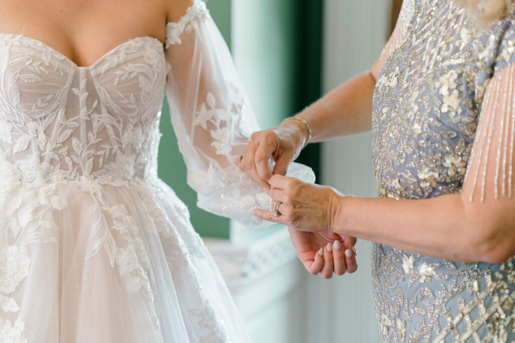 Mother of the bride helps with sleeves on wedding dress. 