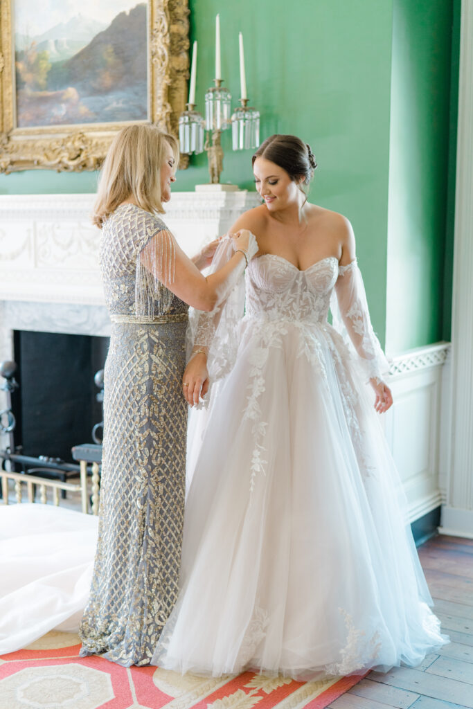 Mother of the bride puts detachable sleeves on daughters wedding dress. 
