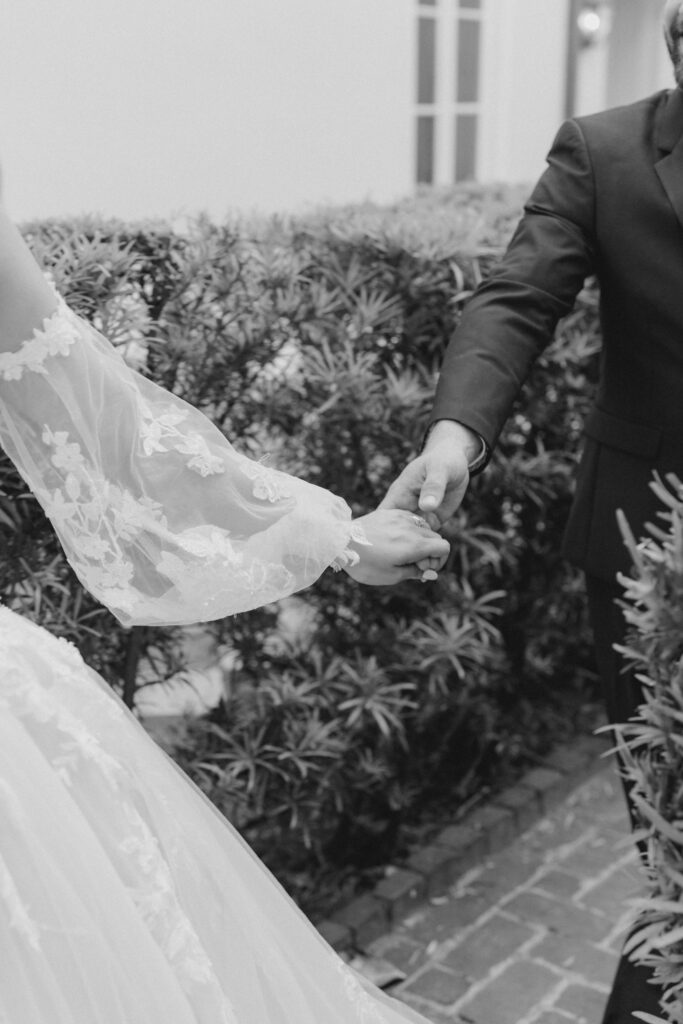 Bride holding grooms hand leading him through the maze at William Aiken House. Black and white wedding photographer.