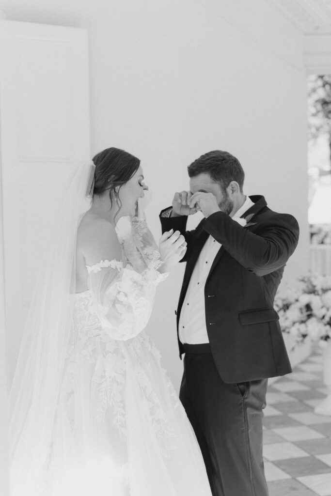 Black and white photo of bride and groom wiping away tears. Photographer good at capturing emotion. 