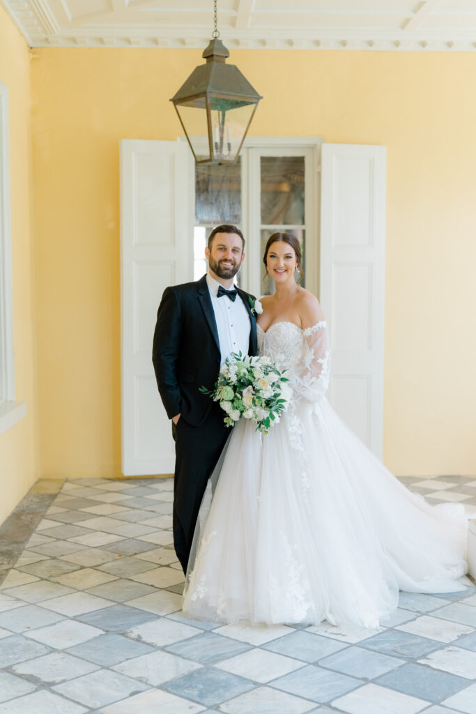 Bride and groom portrait at historic Charleston home with yellow walls and lantern. photographers in Charleston. 