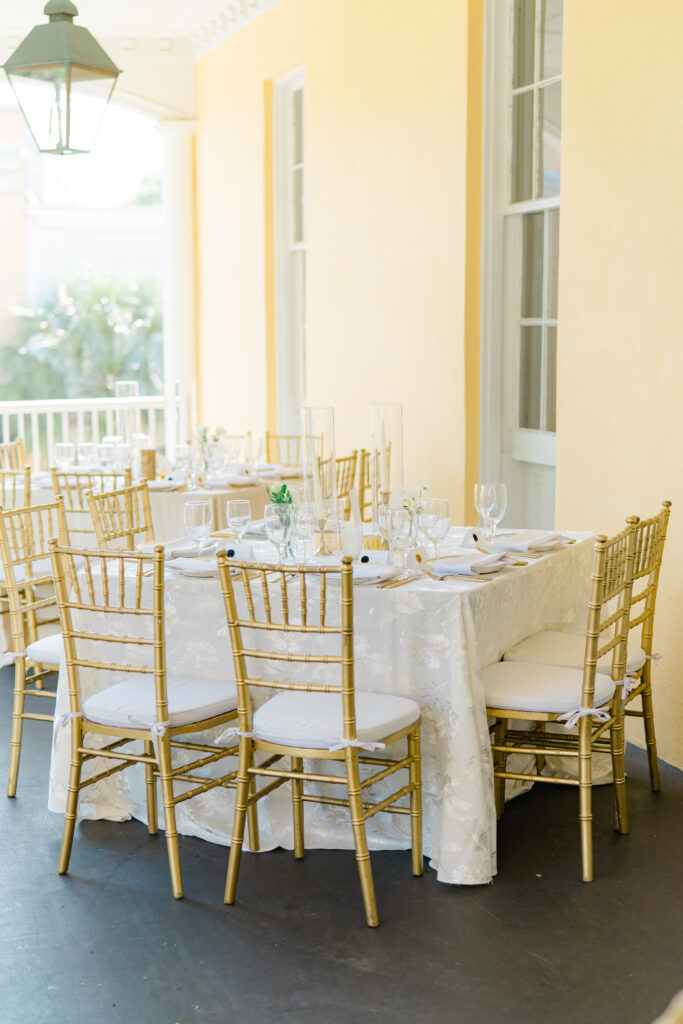 Gold and white wedding reception dinner table on the porch at William Aiken House. 
