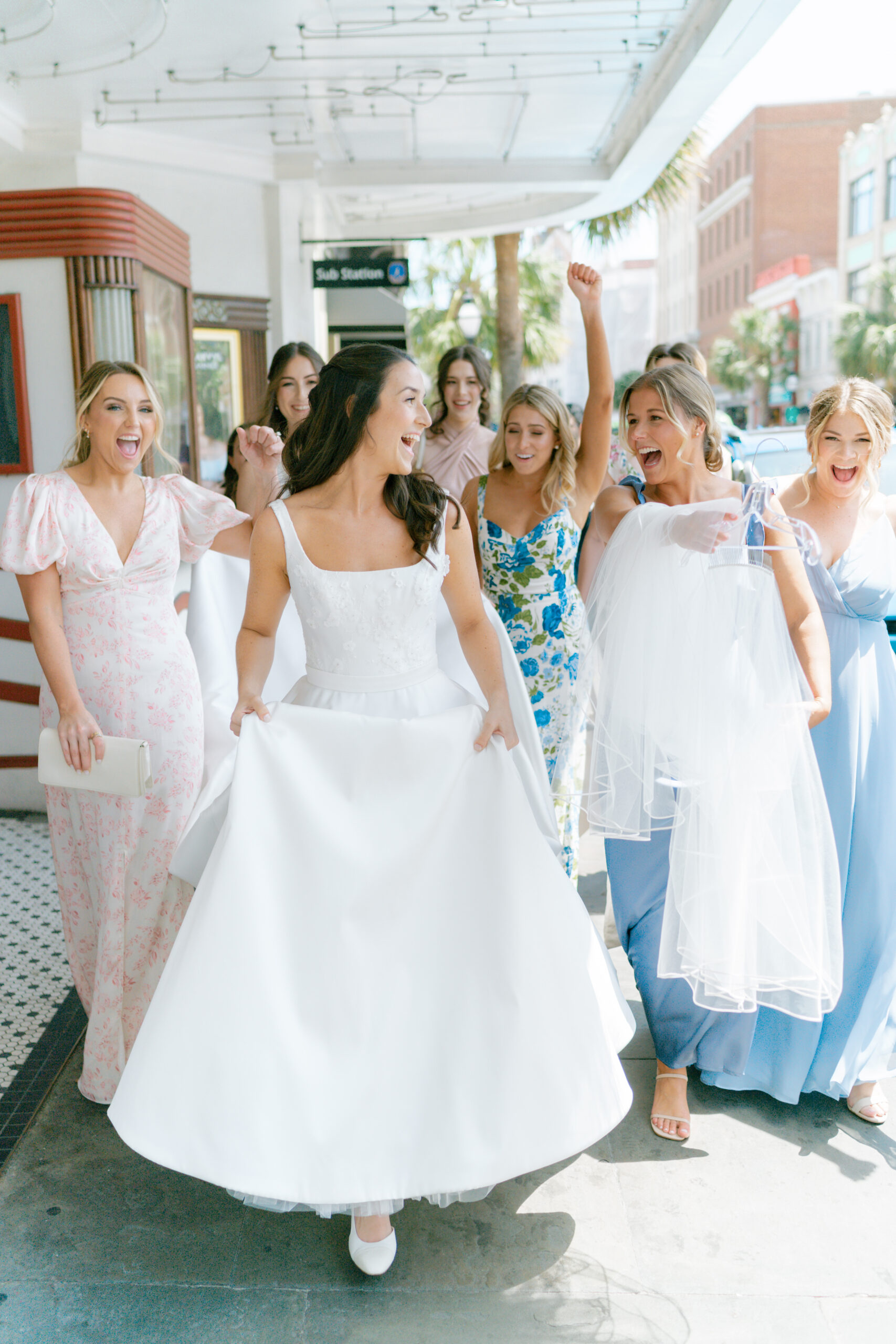 Bridesmaids cheer with bride during walk to William Aiken House wedding ceremony. 