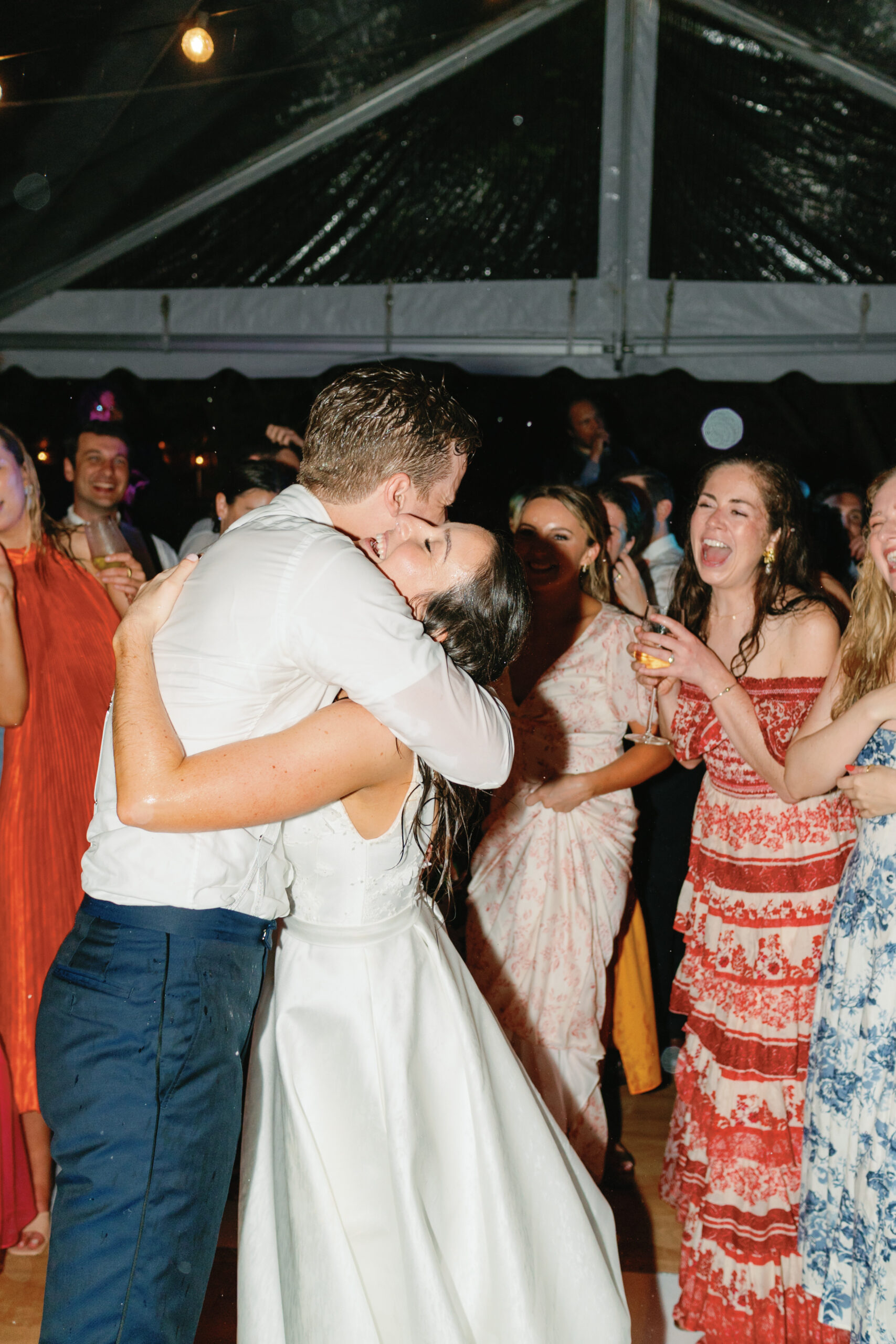 Bride and groom hug on the dance floor with their friends. 