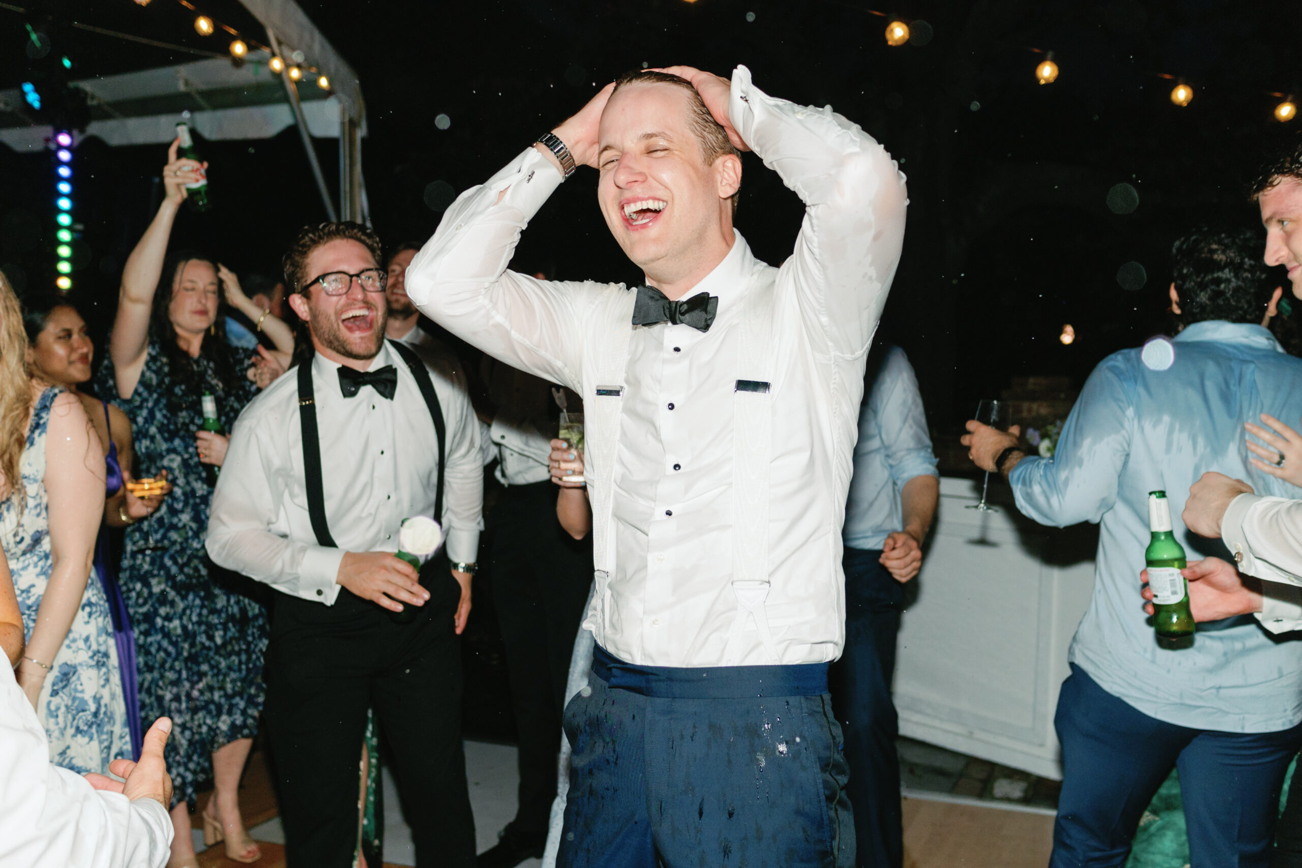 Elated groom on the dance floor. White suspenders and black bow tie. 