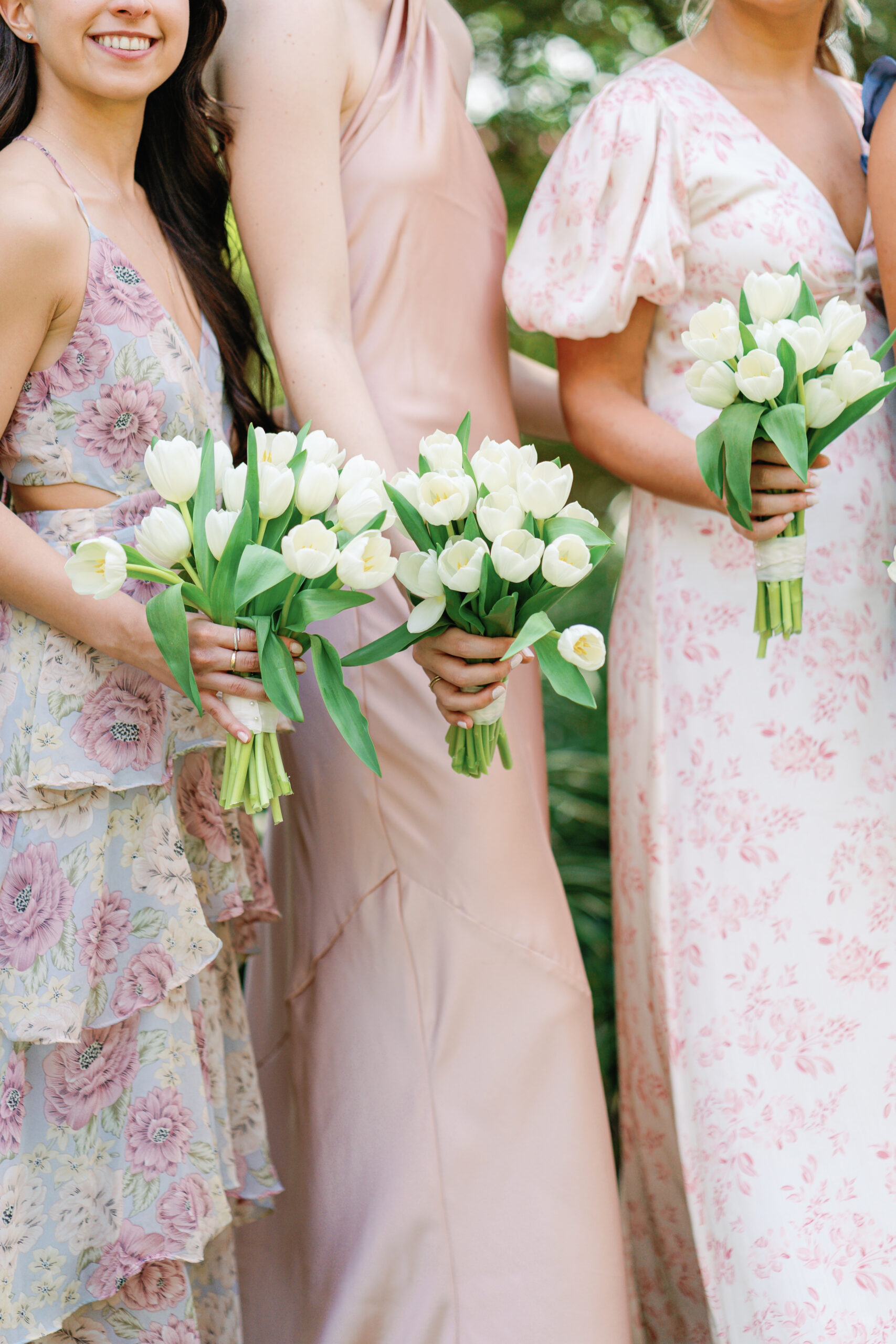 Bridesmaids in mix-matched patterns of pink and purple muted tones with white tulip bouquet. 