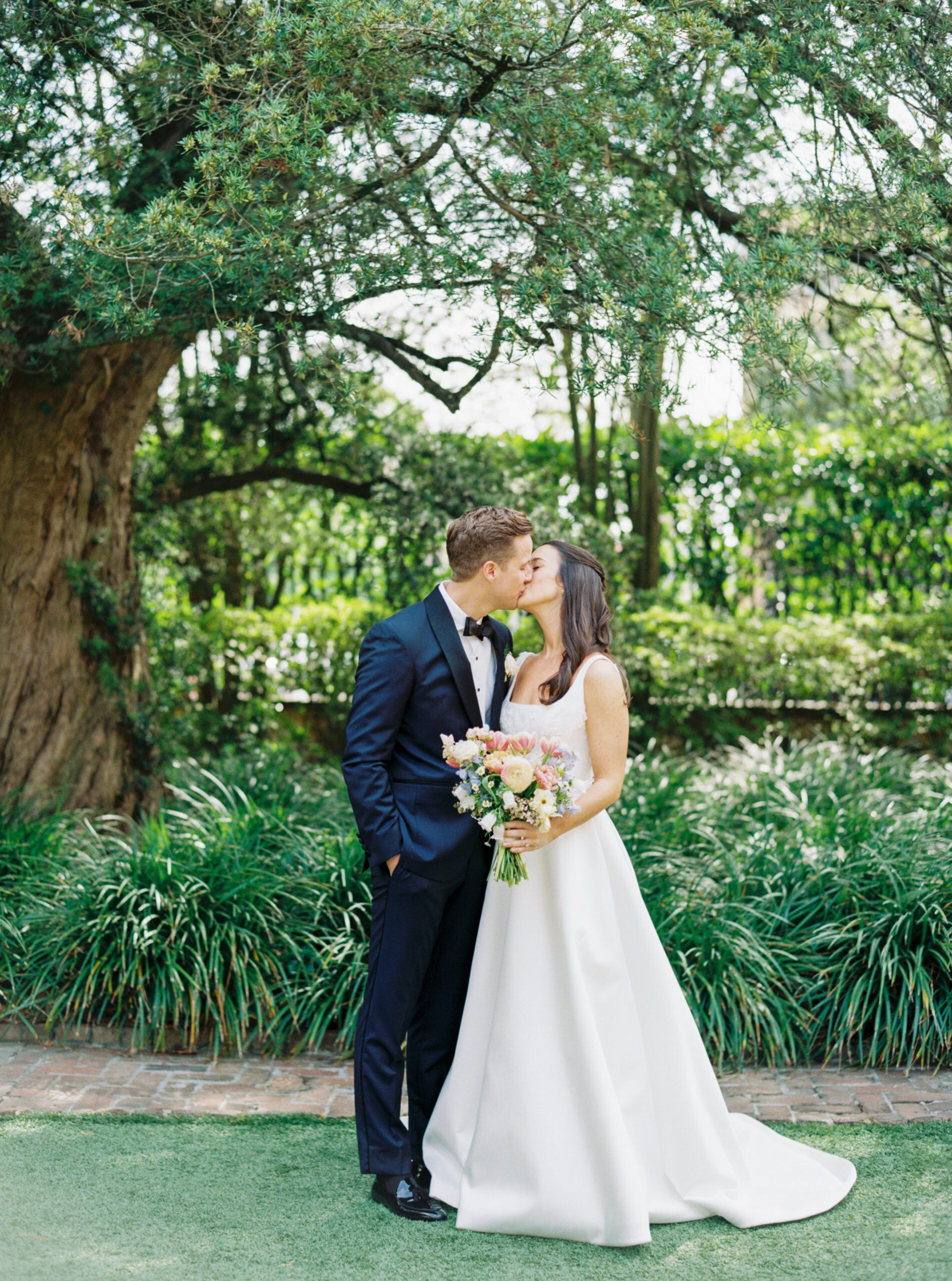 Charleston film photographer. Bride and groom kiss in the garden at william aiken house. 