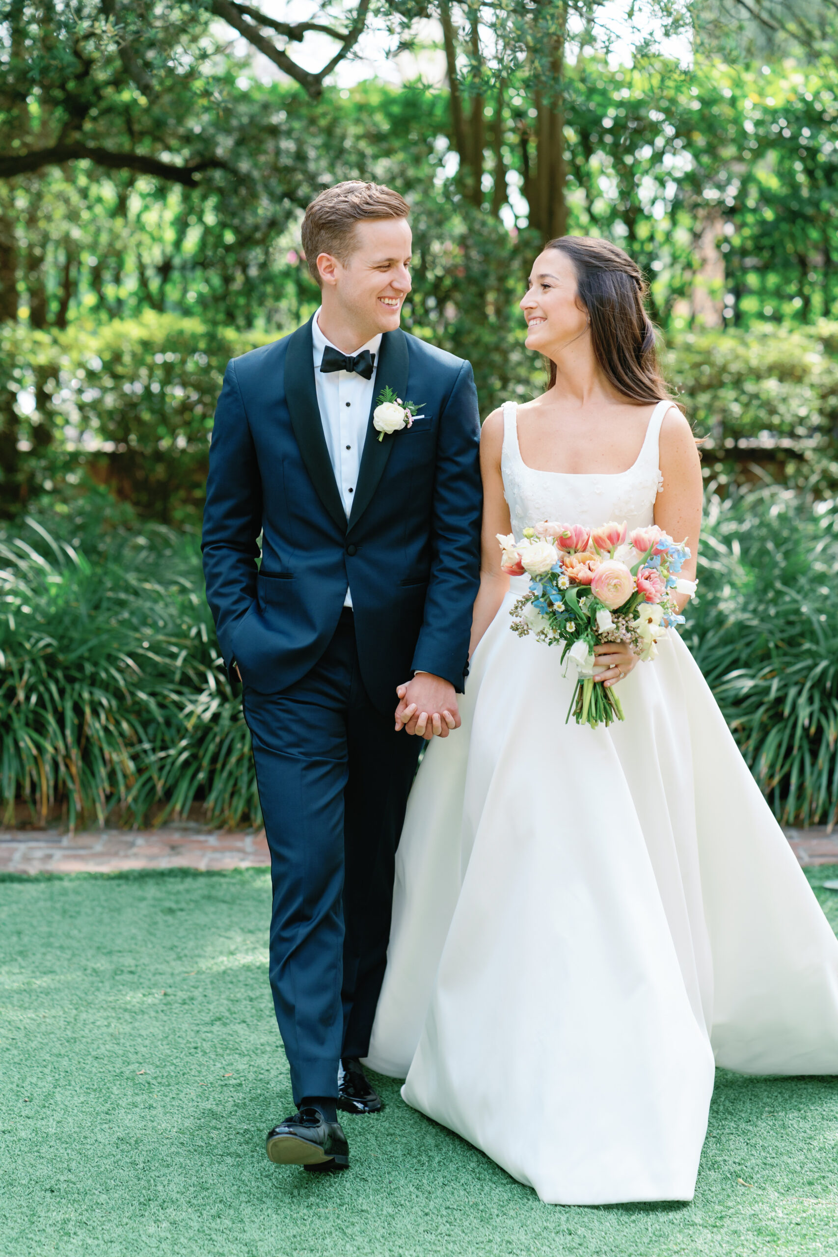Bride and groom laugh while holding hands and looking at each other. Wedding photographers in Charleston, SC