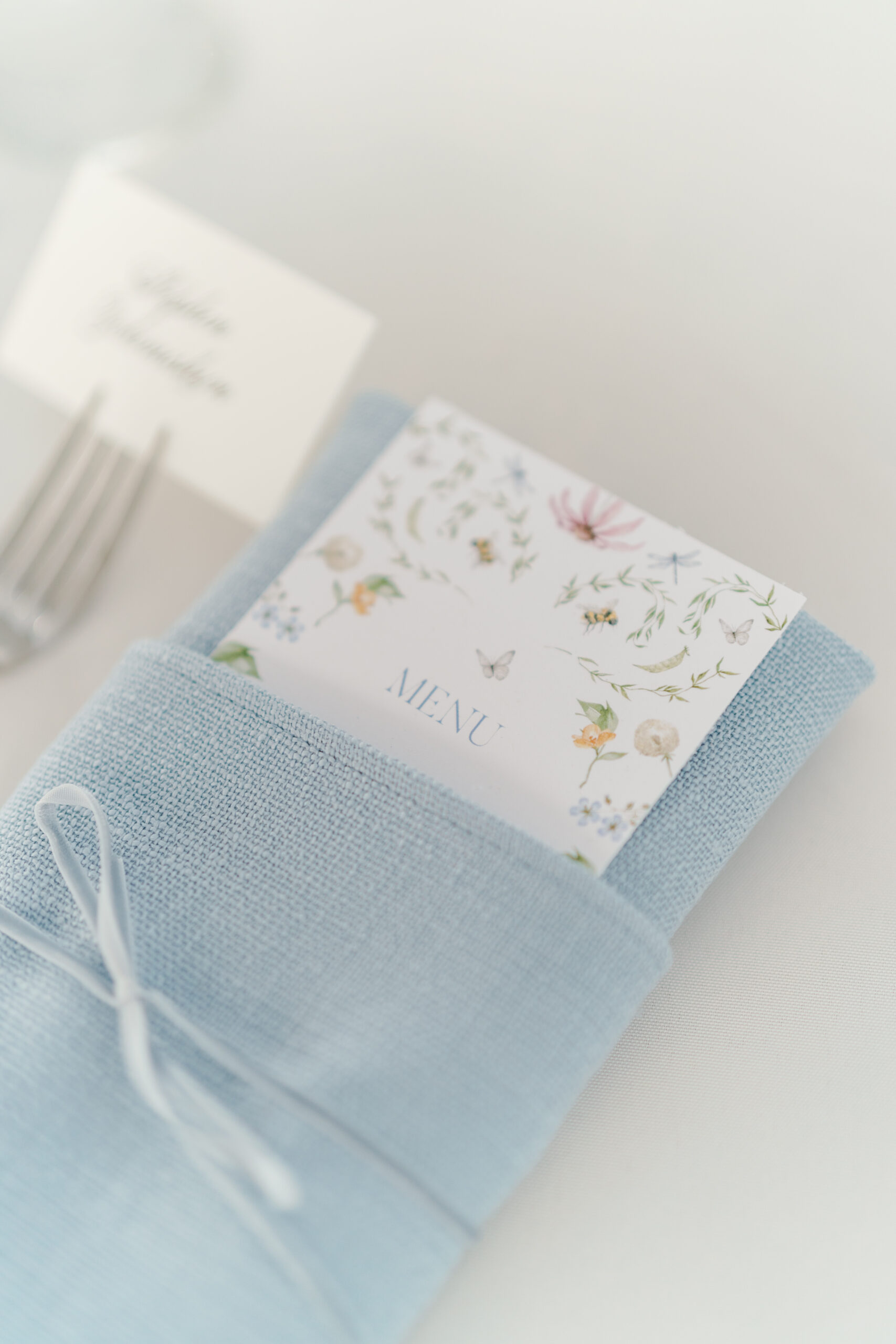 Wildflower themed wedding reception food menu. Bees and butterflies. Light blue linen napkin.