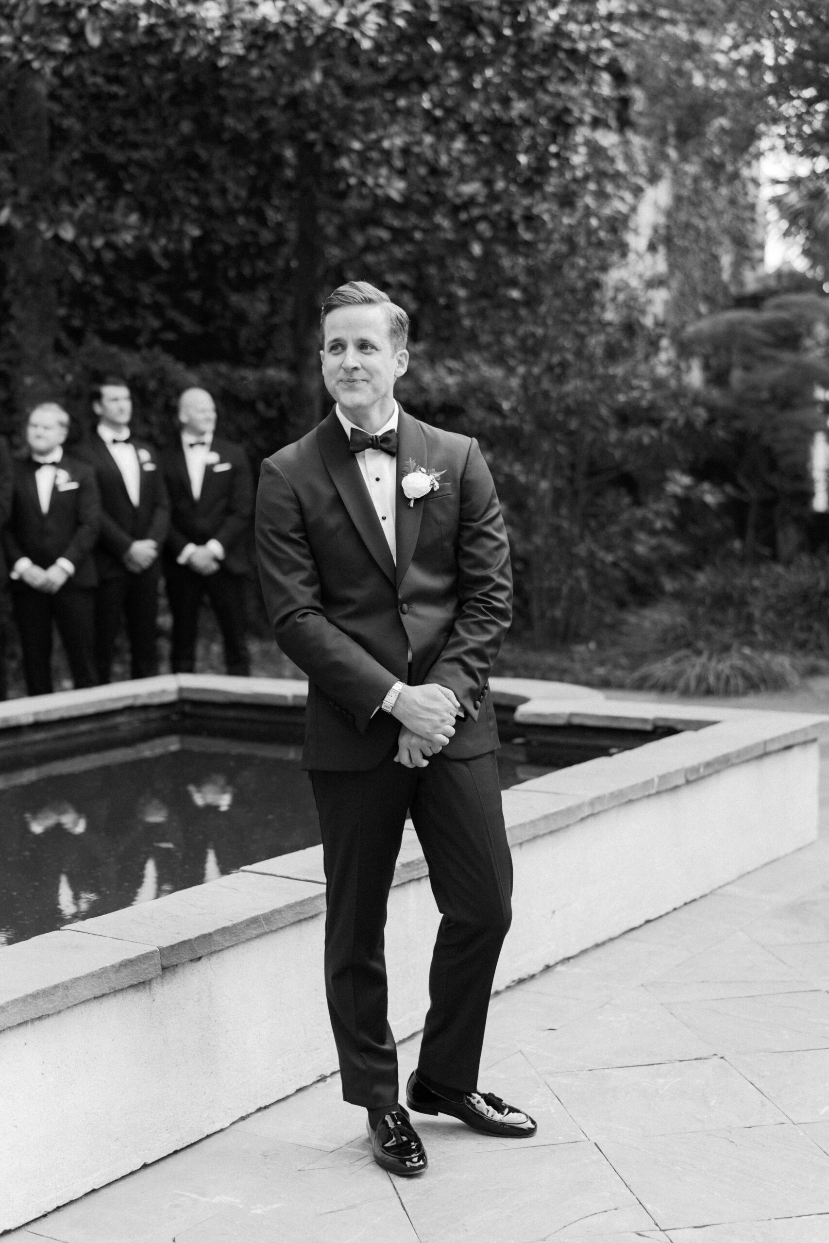 Black and white photo of groom getting emotional before outdoor wedding ceremony in Charleston, SC. 