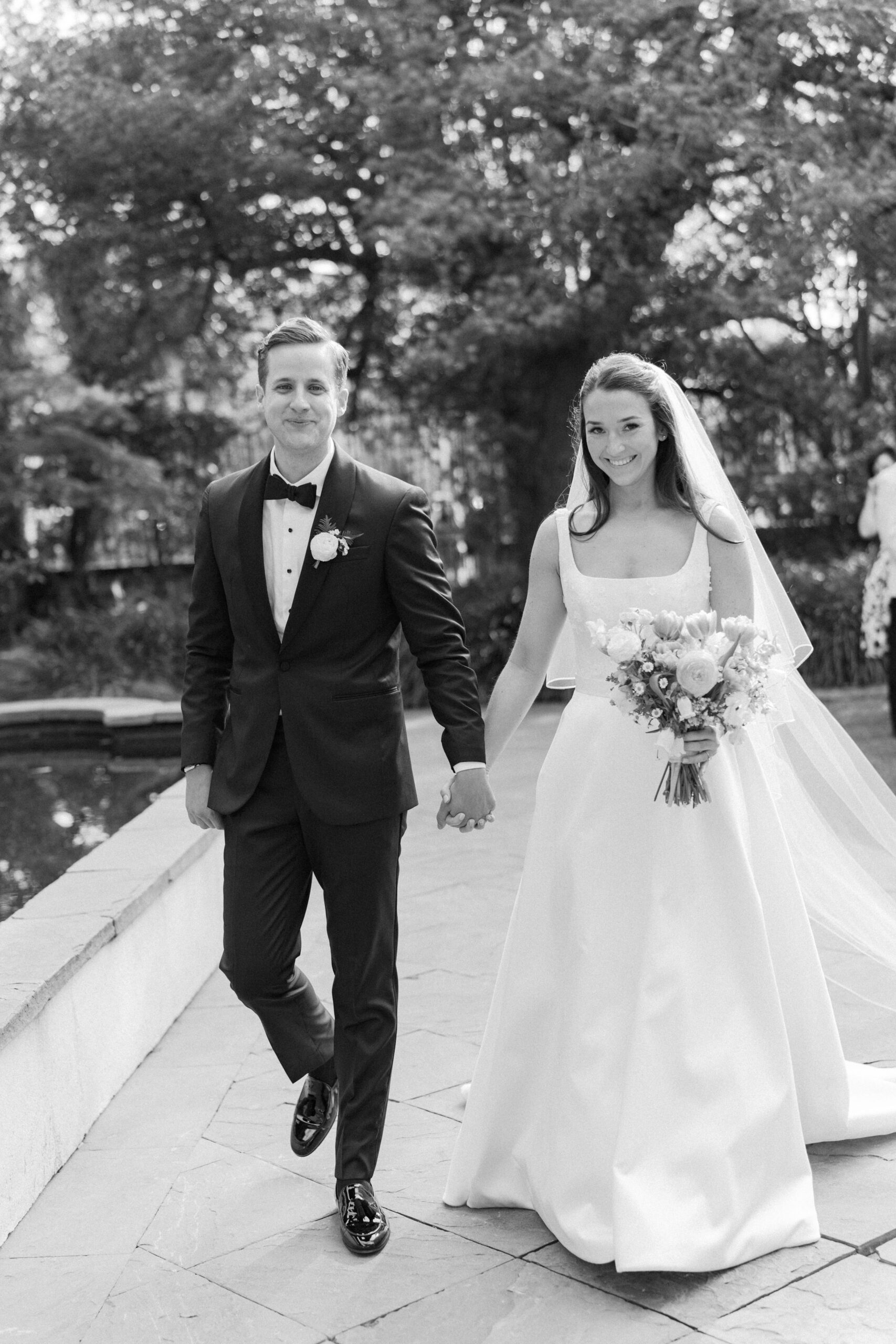Black and white photo of bride and groom holding hands and walking to wedding ceremony. Charleston photographer. 