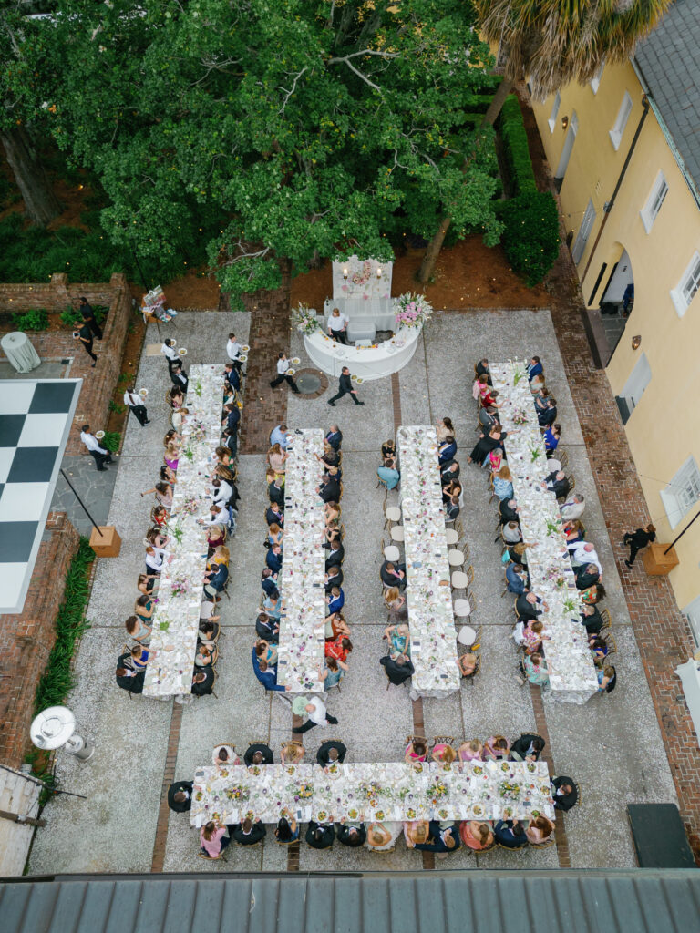 Wedding reception outdoor dinner with long tables and curved bar. Plated dinner service. 