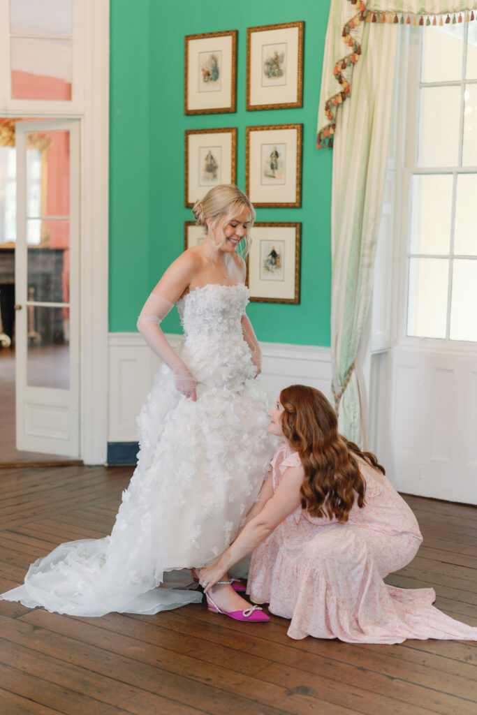 maid of honor helps bride put on wedding day heels. Charleston sc wedding photographer