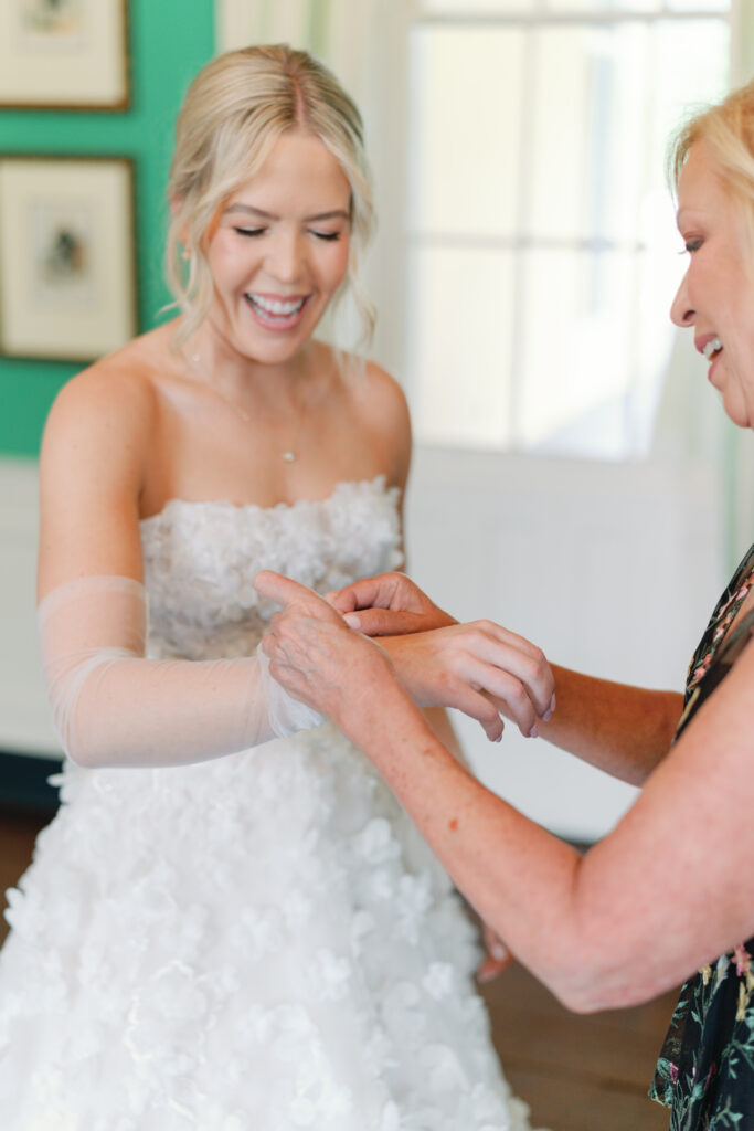 Mother of the bride helps daughter with sleeves on wedding dress. charleston photographers.