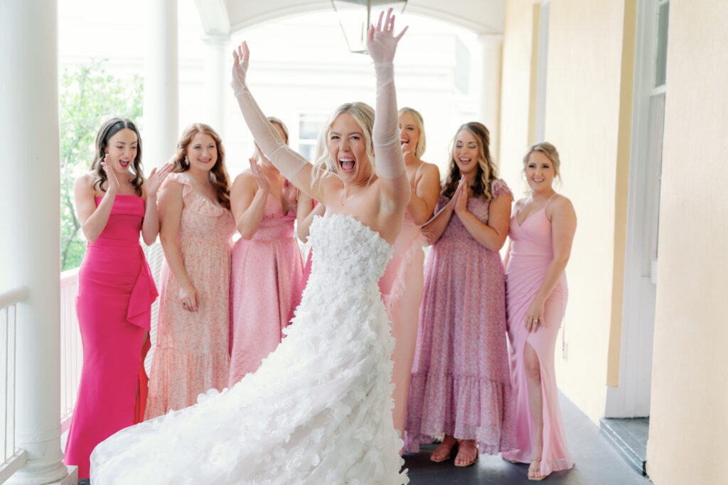 Bride twirls to show off her dress to bridesmaids. wedding photographers in Charleston. 