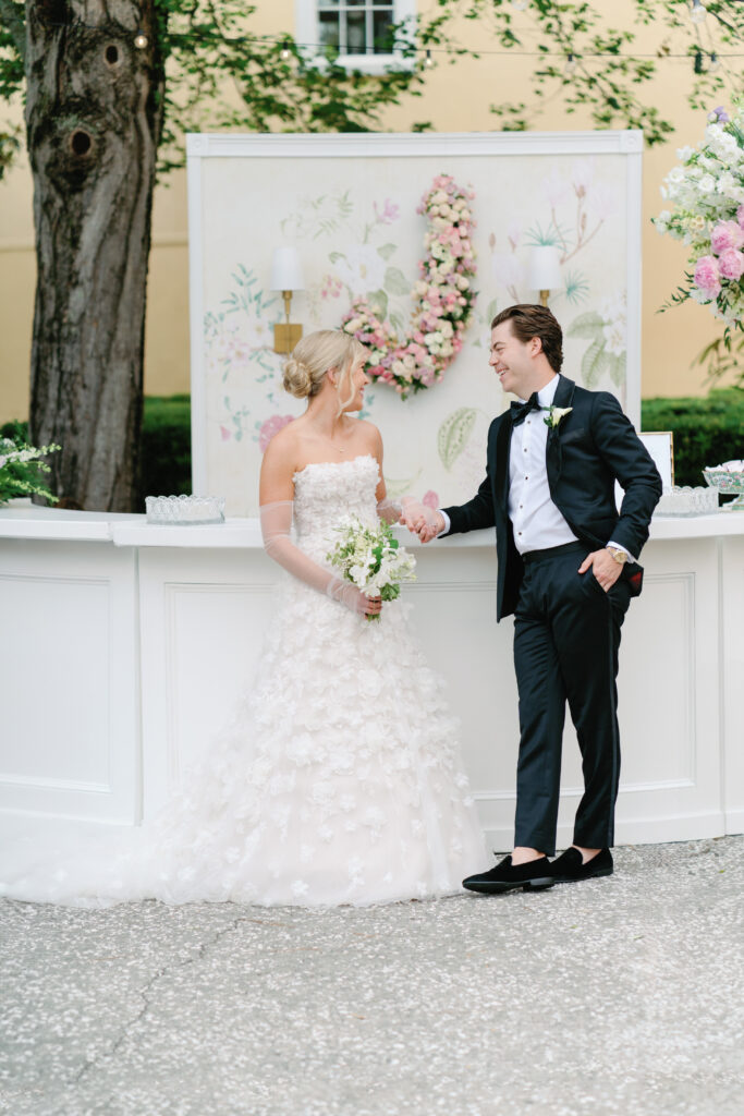 Bride and groom posing in front of custom bar floral installation 
