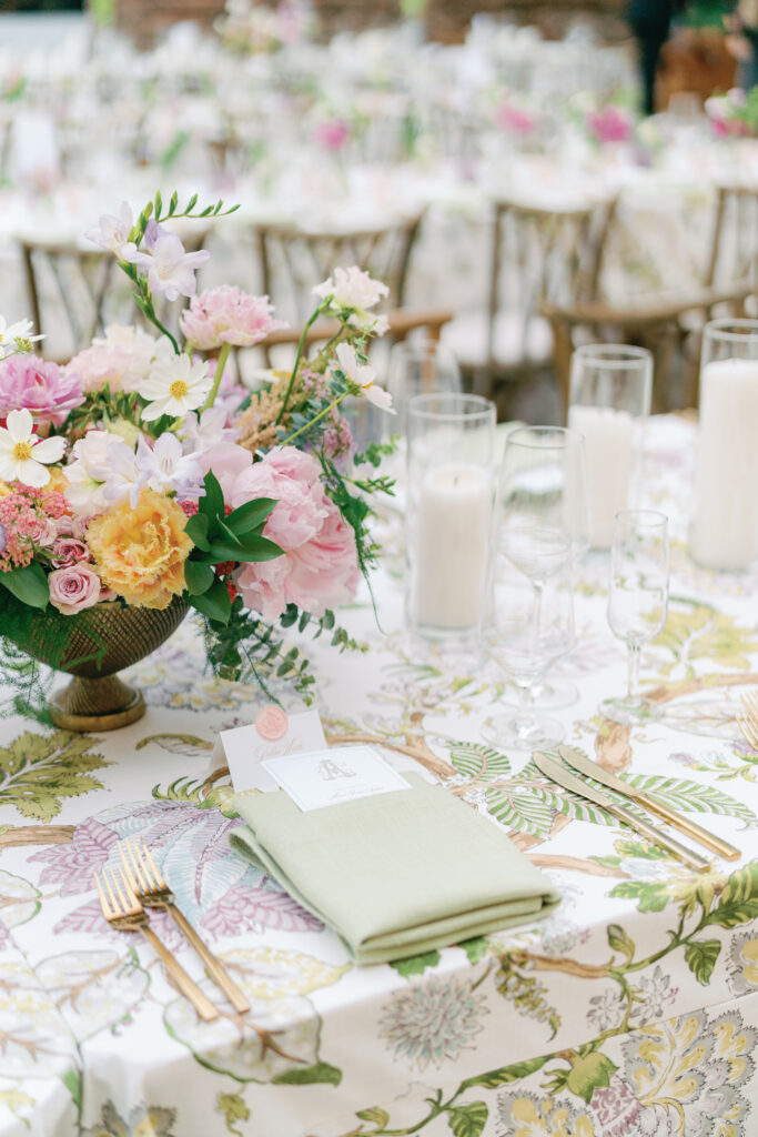 Pink, purple, yellow, and green wedding reception florals with gold utensils and pale green napkins. Open air william aiken house wedding reception dinner.