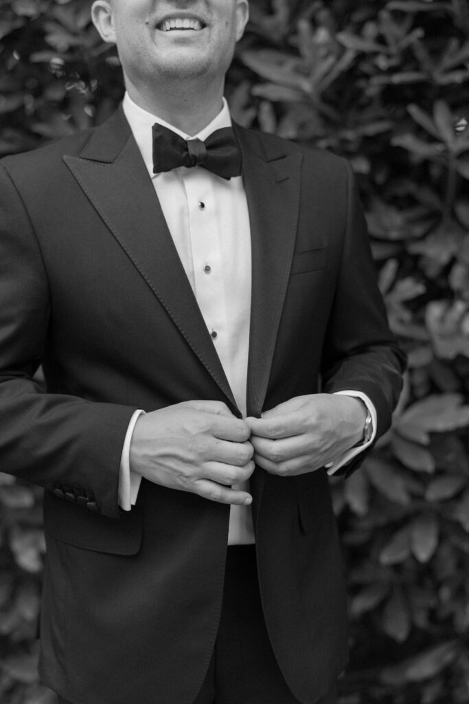 Groom buttoning tuxedo jacket. Highlands NC destination wedding photographer. 