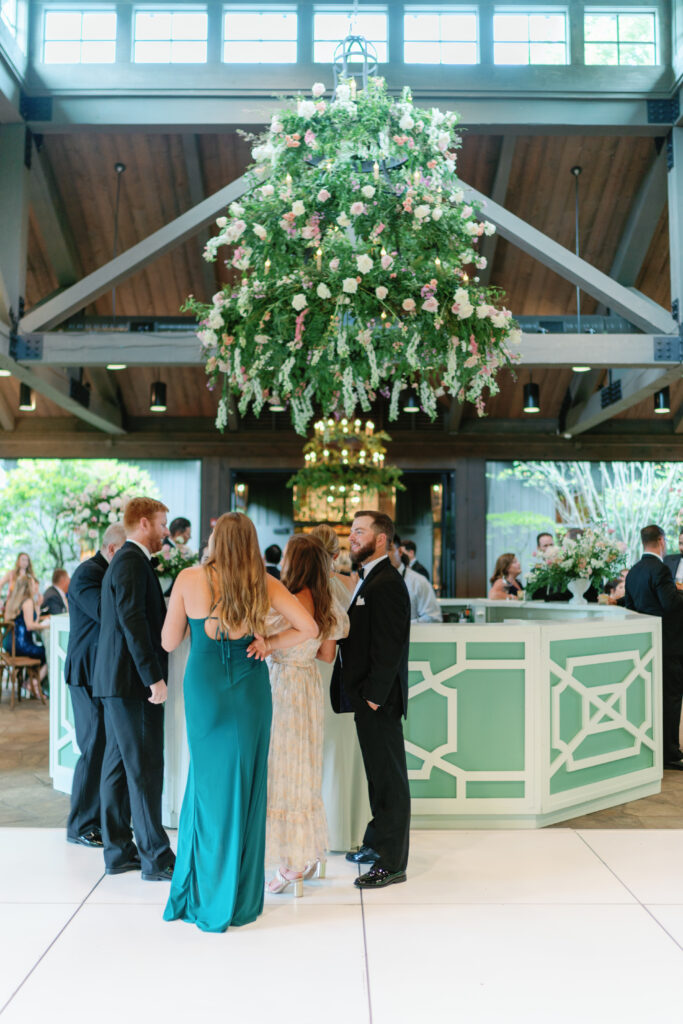 Wedding guests at white and green bar in the pavilion at old edwards.