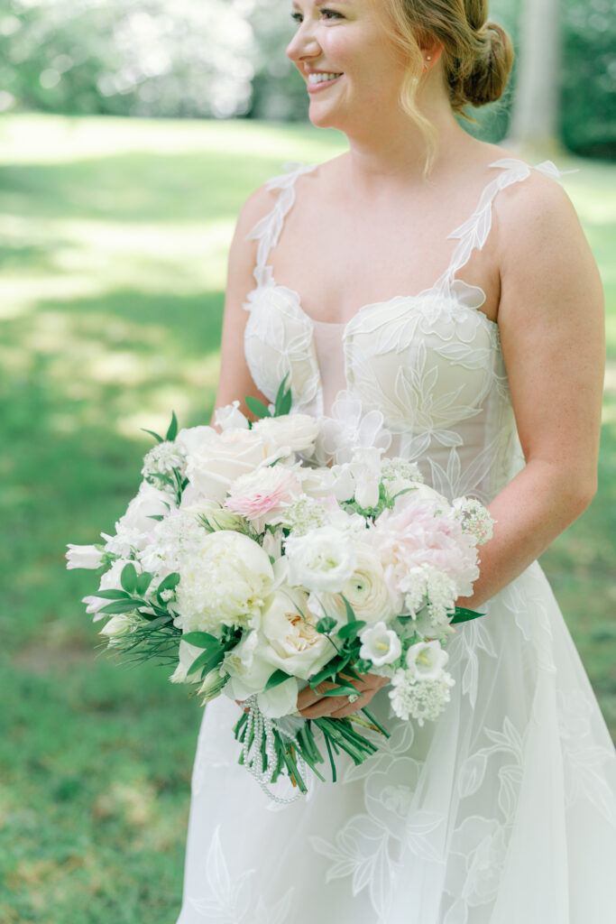 Bride holding wedding day bouquet. White flowers wit touches of pale pink. photographer highlands nc.