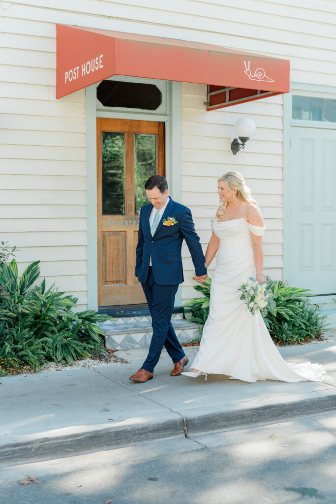 Bride and groom walking on the sidewalk in front of Post House Inn. 