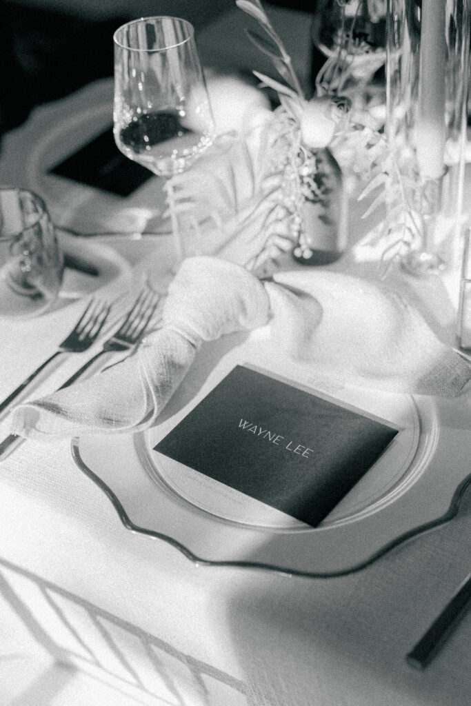 Black and white photo of sun hitting dinner place setting at Post House Inn wedding.