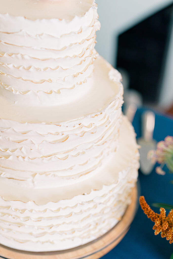 Cream colored wedding cake with fringes of gold on rim design. 