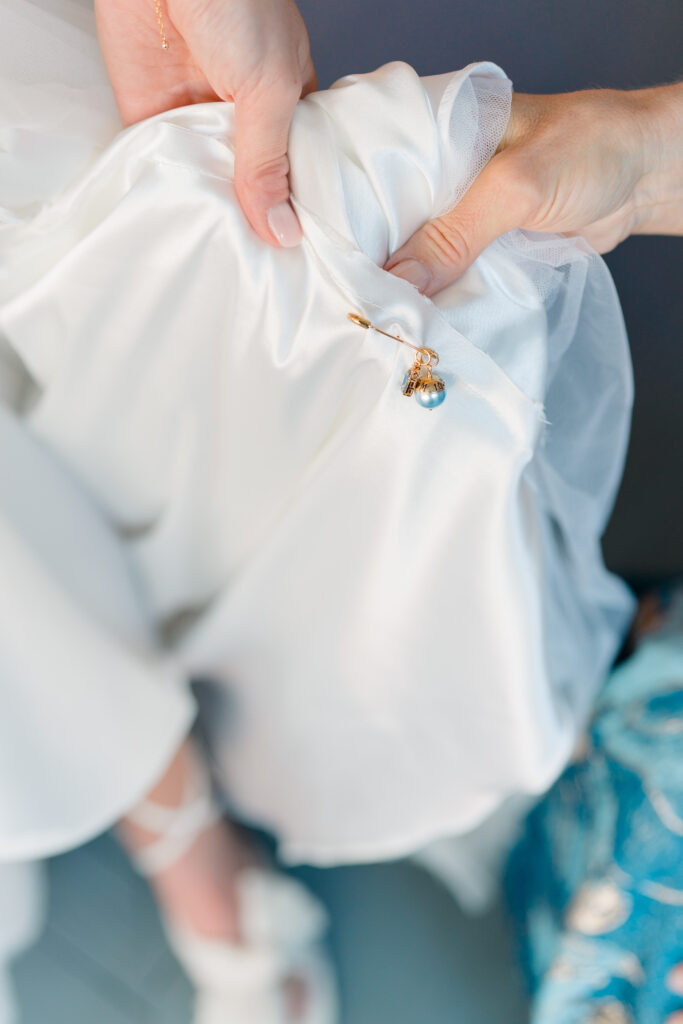 Bride pins her something blue to the inside of her wedding dress.