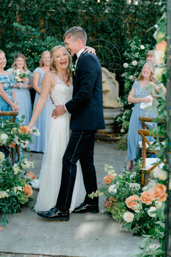 Fun moment as bride and groom laugh at each other after wedding ceremony aisle dip kiss. 