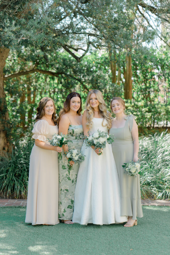 Bride and three bridesmaids in mix matched green and tan dresses. 