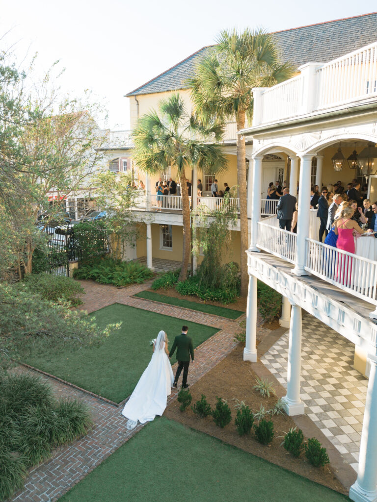 Bride and groom walking to cocktail hour on the porches of William Aiken house. 